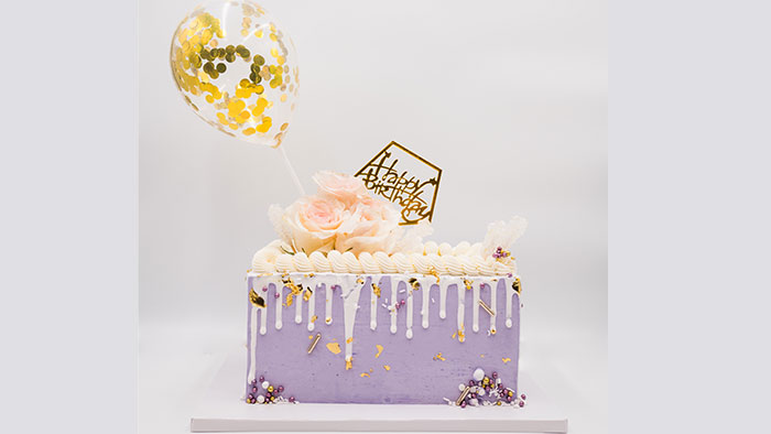 A purple frosted Birthday Cake with a Birthday Balloon