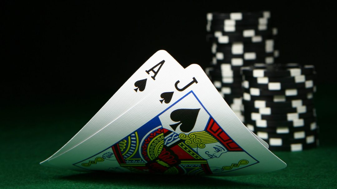 Ace and Jack cards in front of pile of black and white poker chips